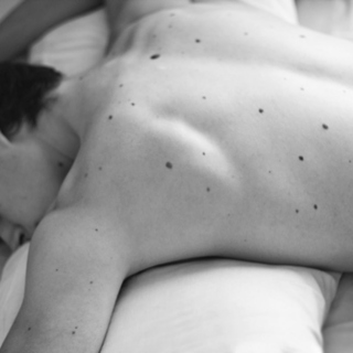 I trace the freckles on your back like constellations